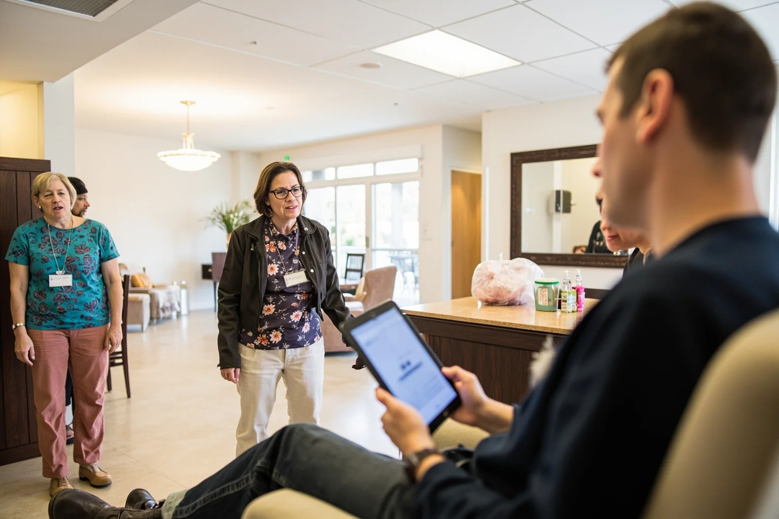 A woman touring a rehabilitation center, speaking with recovering residents in a bright common room