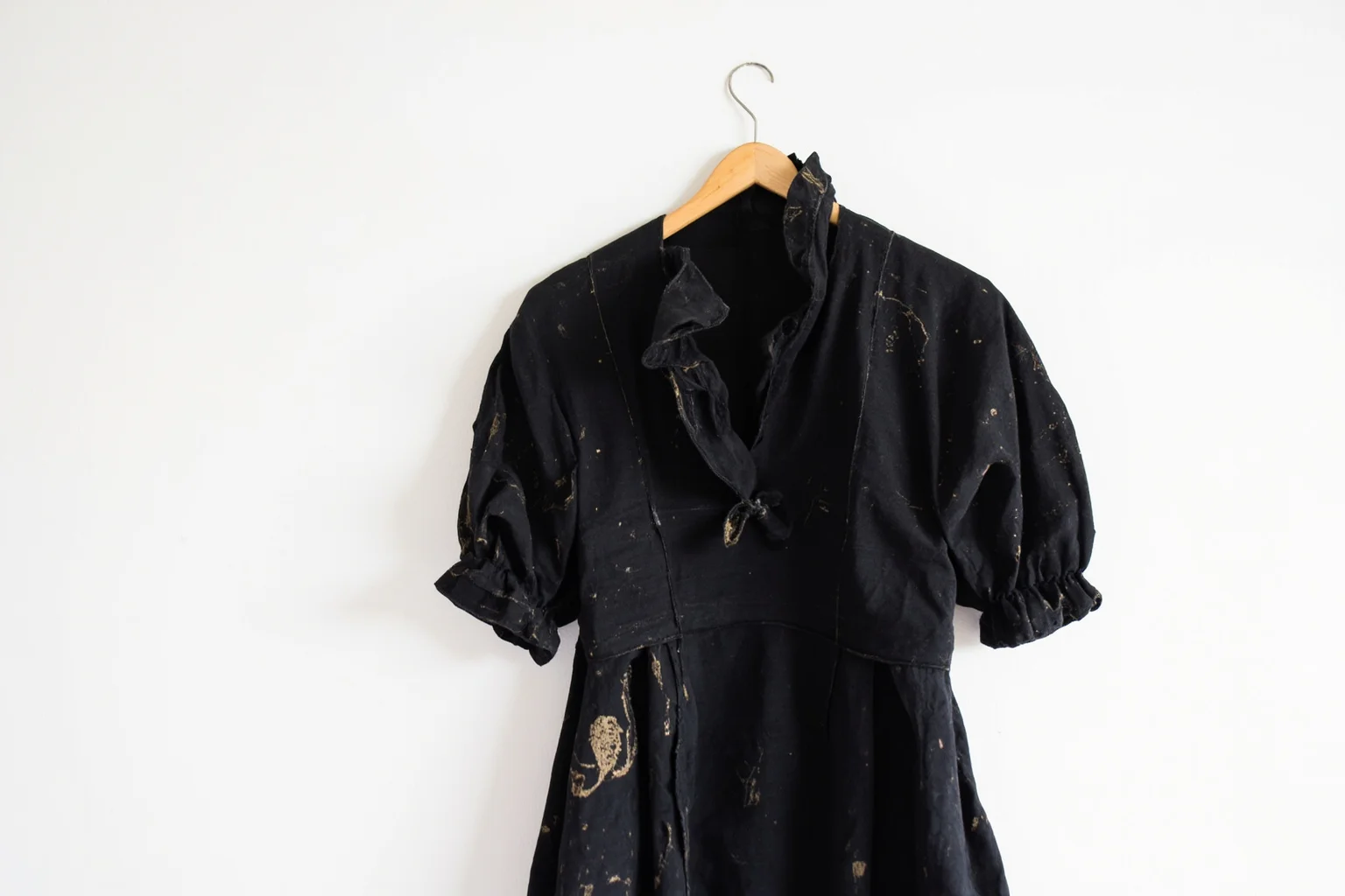 23 Facts About Hetty Green, the Billionaire Who Lived Like a Beggar 10 A worn, patched black Victorian dress hanging on a simple wooden hanger, minimalist still-life illustration