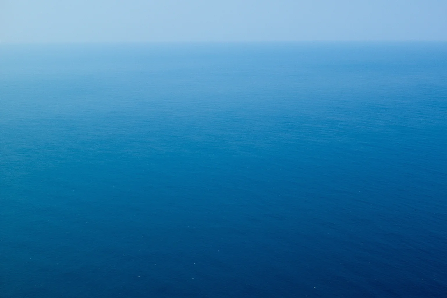 22 Ocean Mysteries We Still Haven't Solved 8 Aerial view of an empty, featureless expanse of deep blue ocean stretching to the horizon