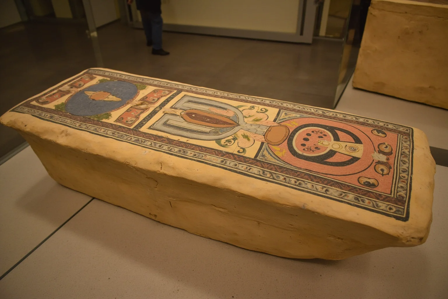 An ancient Egyptian painted coffin lid displayed in a museum hall