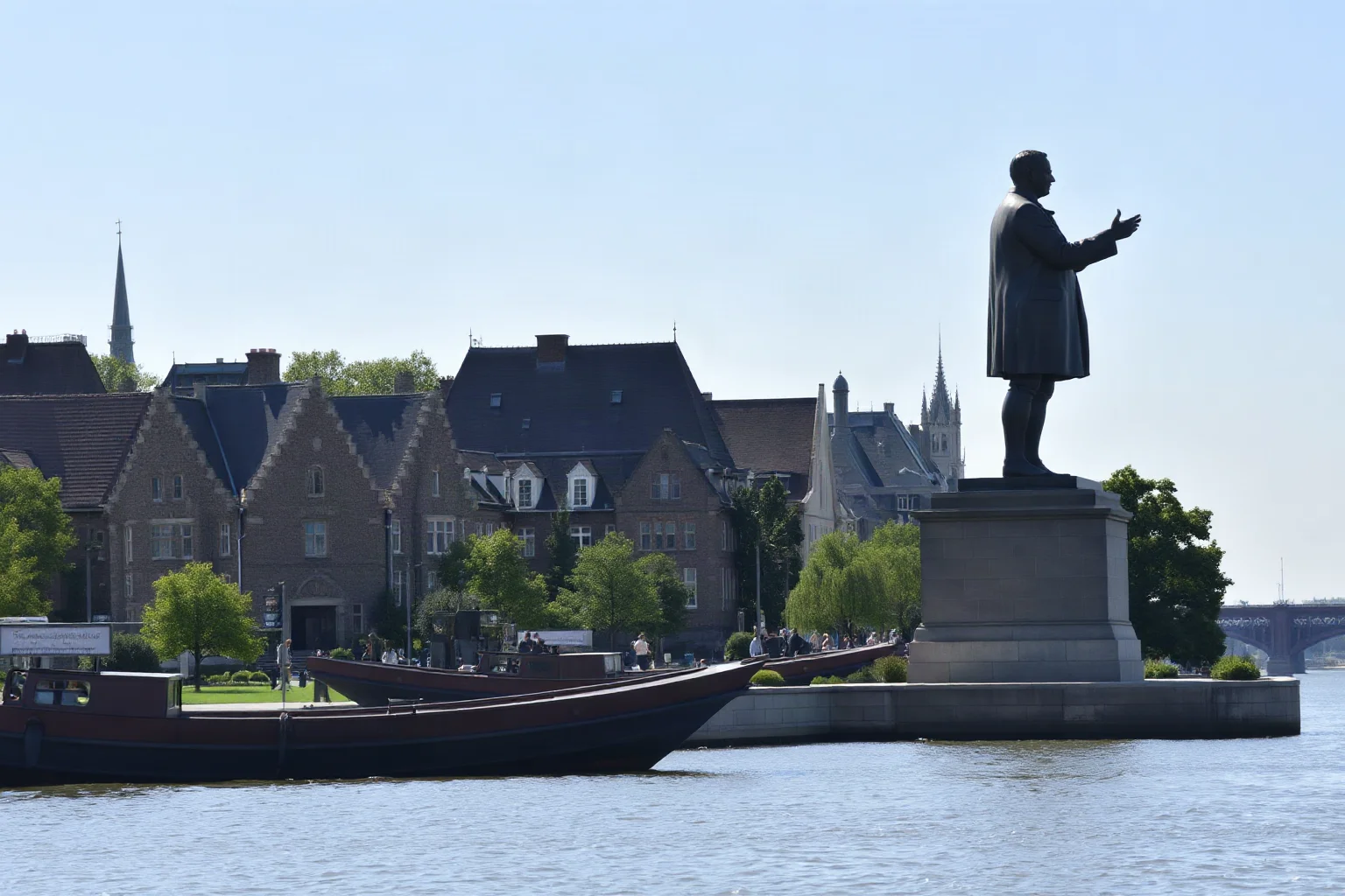 An enormous bronze-toned statue of a historical statesman standing on a riverside platform