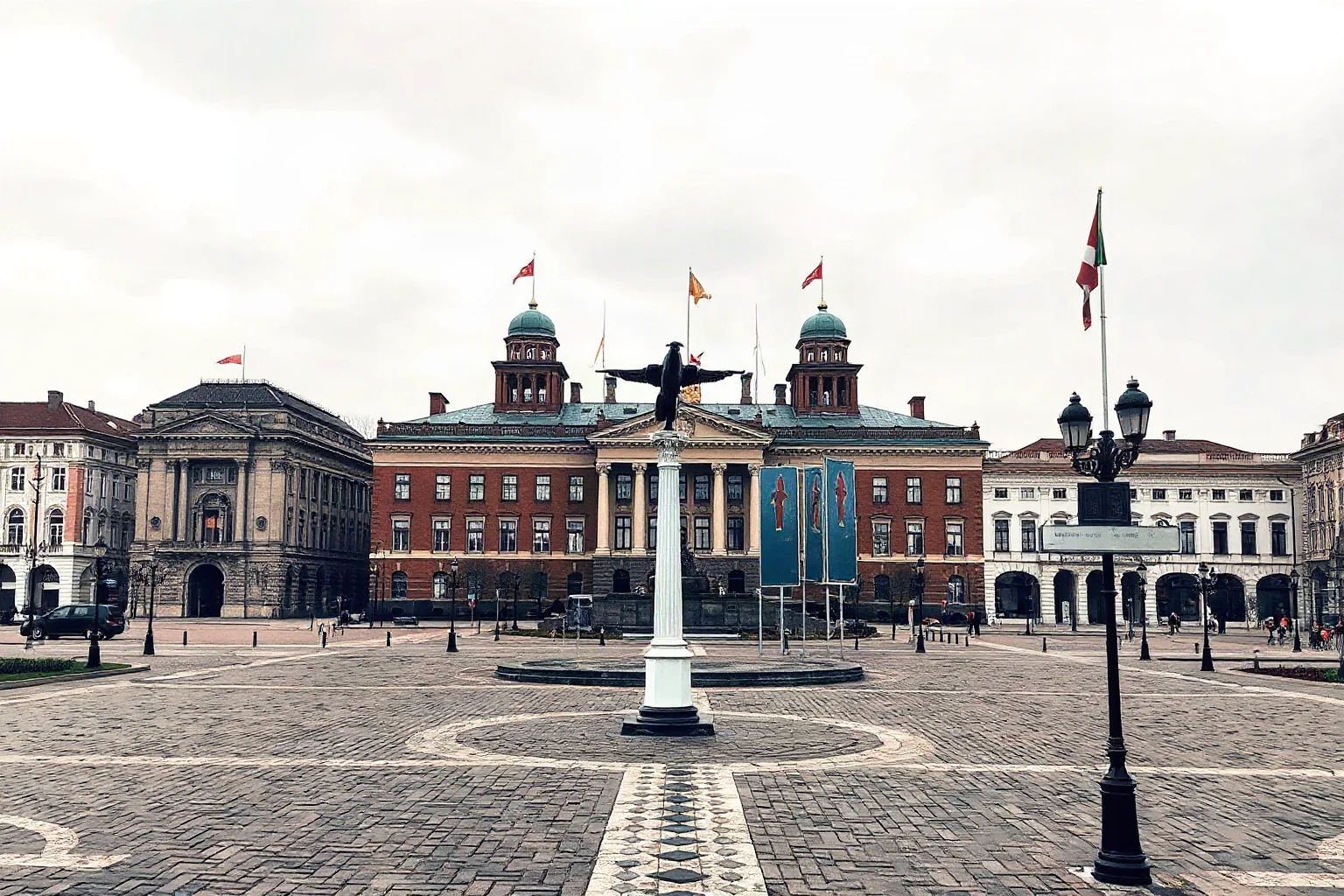 An illustrated 1980s Eastern European city square with grand communist-era government buildings and gray skies