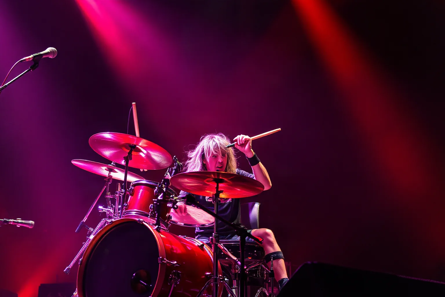 An intense thrash metal drummer playing rapidly under harsh red stage lighting