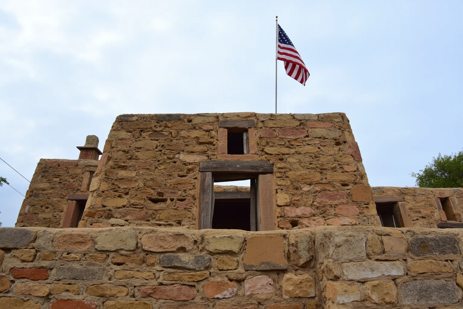 An old adobe and stone Spanish presidio fort building with an American flag