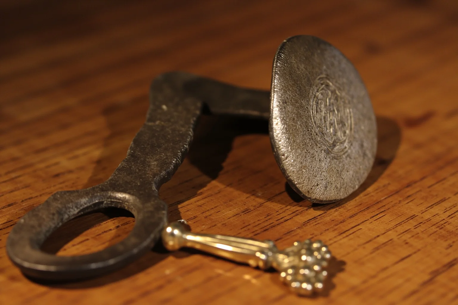 Brutal Forms of Public Humiliation Throughout History 16 An old iron branding tool and small ornate hand mirror on a wooden table, symbolic historical illustration