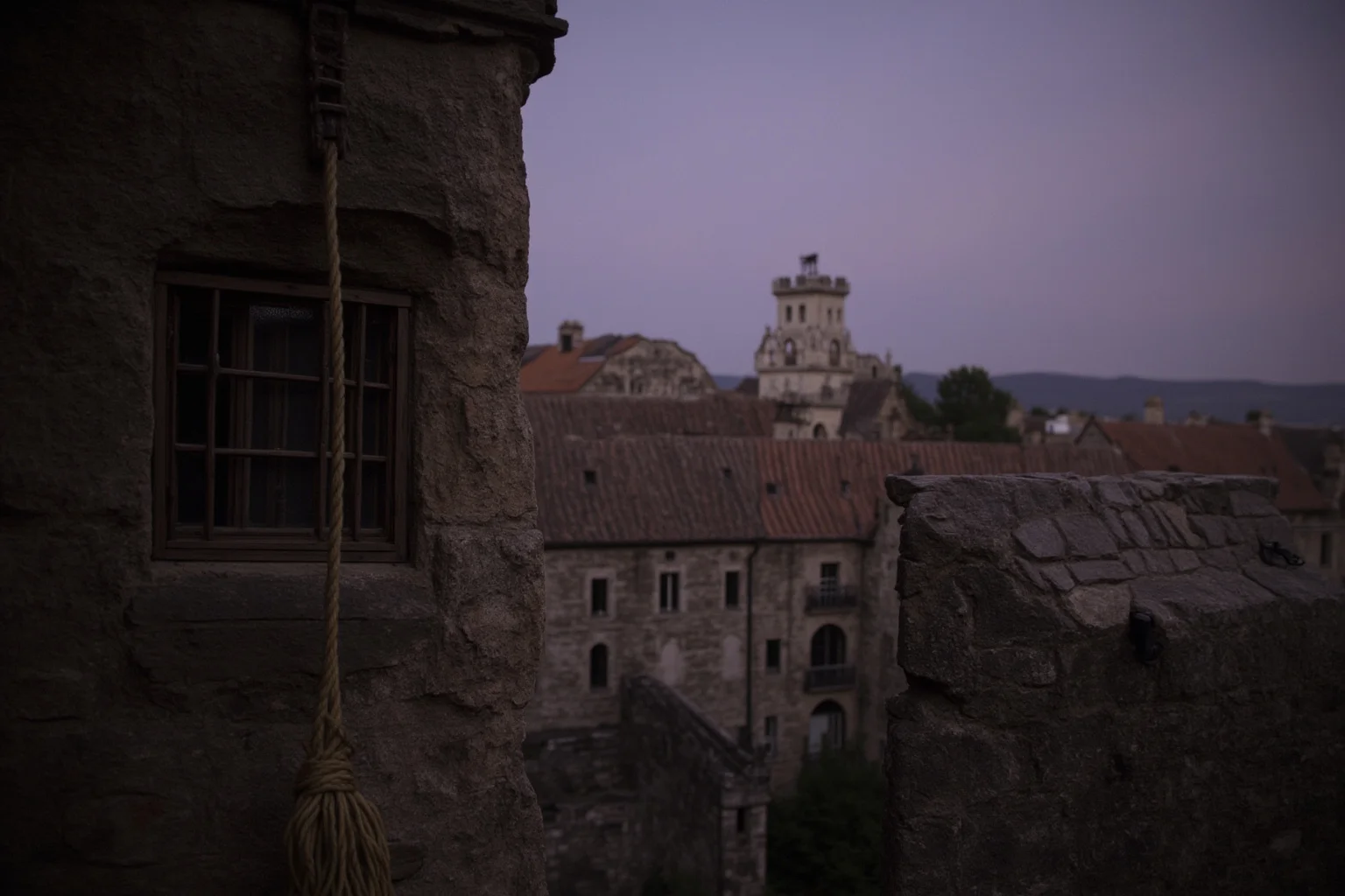 The Most Daring Prison Escapes in History 20 An old stone European castle at dusk with a rope dangling from a high window