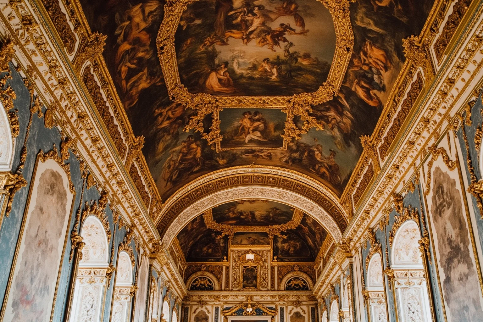 An ornate French Renaissance palace gallery interior with decorative frescoed walls and gilded details