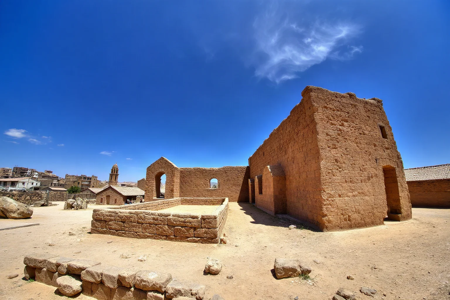 Ancient mudbrick church ruin under a desert sky near a historic port town, sun-bleached walls, wide-angle archaeological photo