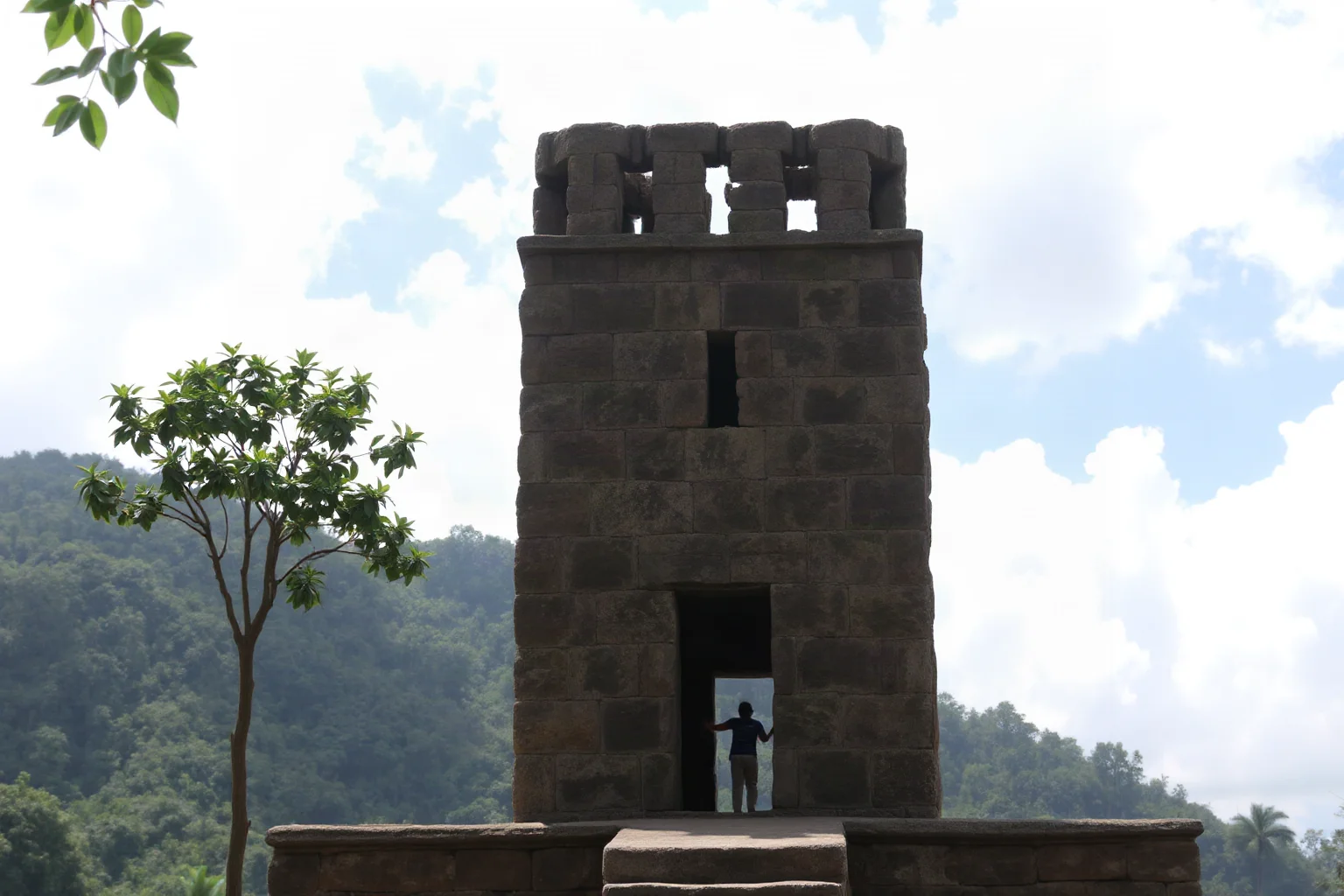 Ancient stone observatory tower with small windows aligned to the sky, jungle backdrop