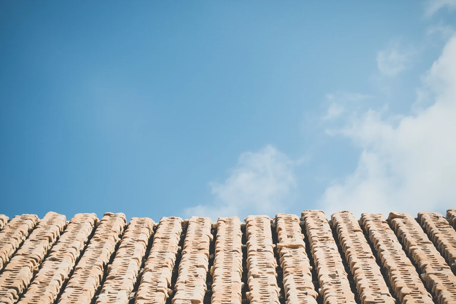 Ancient temple rooftop covered in interlocking marble tiles under a clear blue sky
