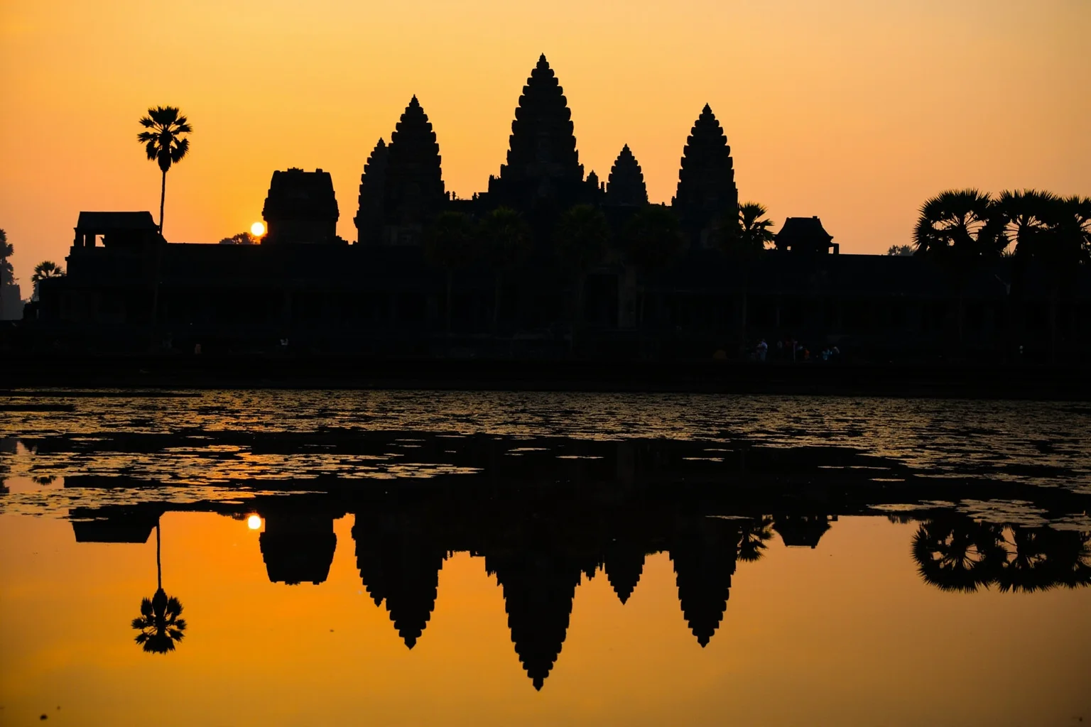 Angkor Wat's ancient temple towers reflected in a lotus pond at sunrise