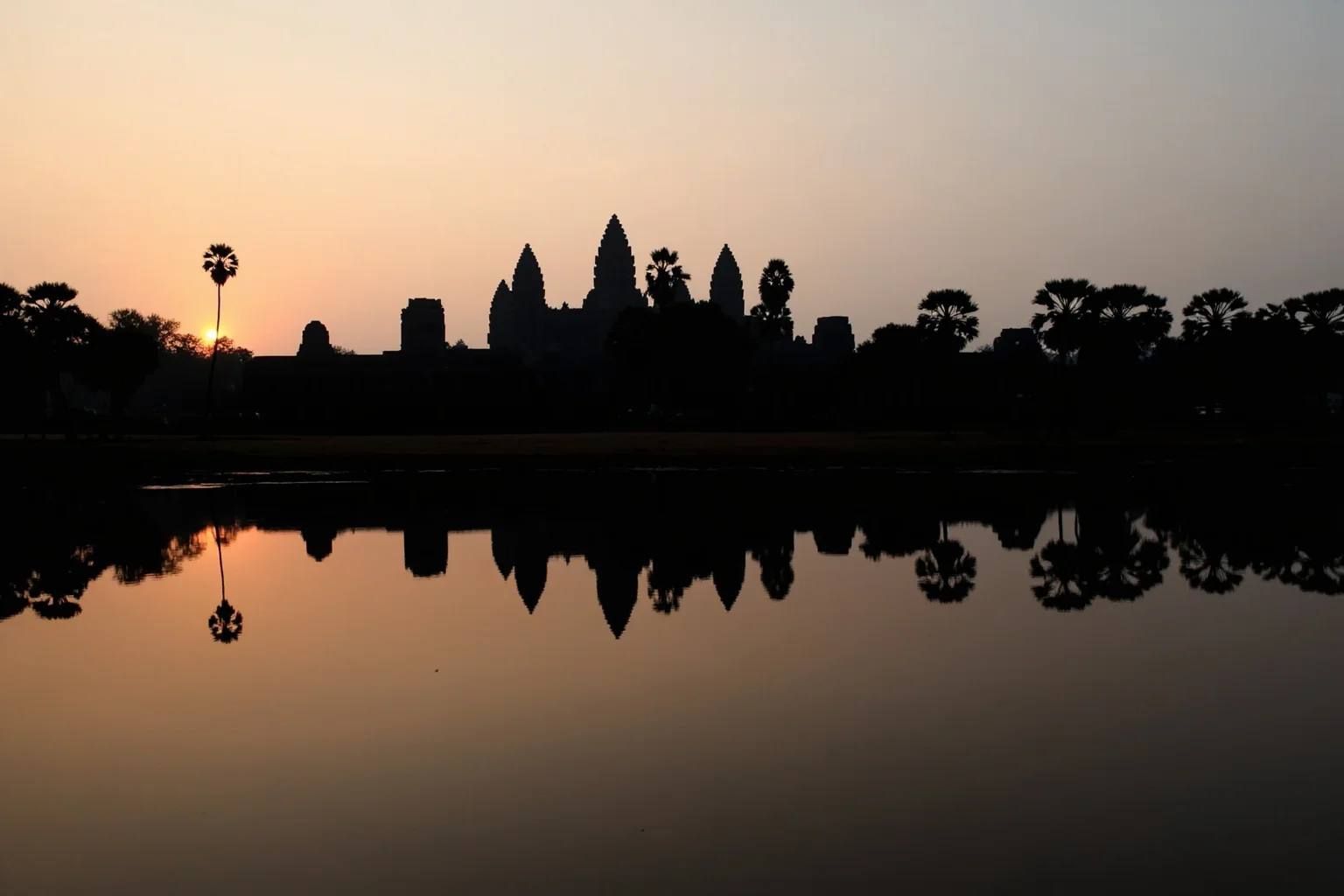 Angkor Wat's temple towers reflected in its surrounding moat at sunrise