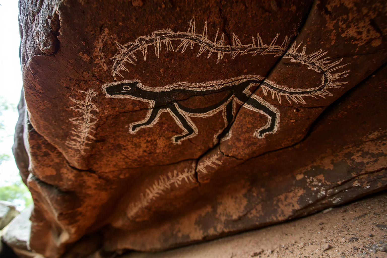 Charcoal drawing on a rock shelter ceiling depicting an ancient figure or animal, Aboriginal Australian rock art style