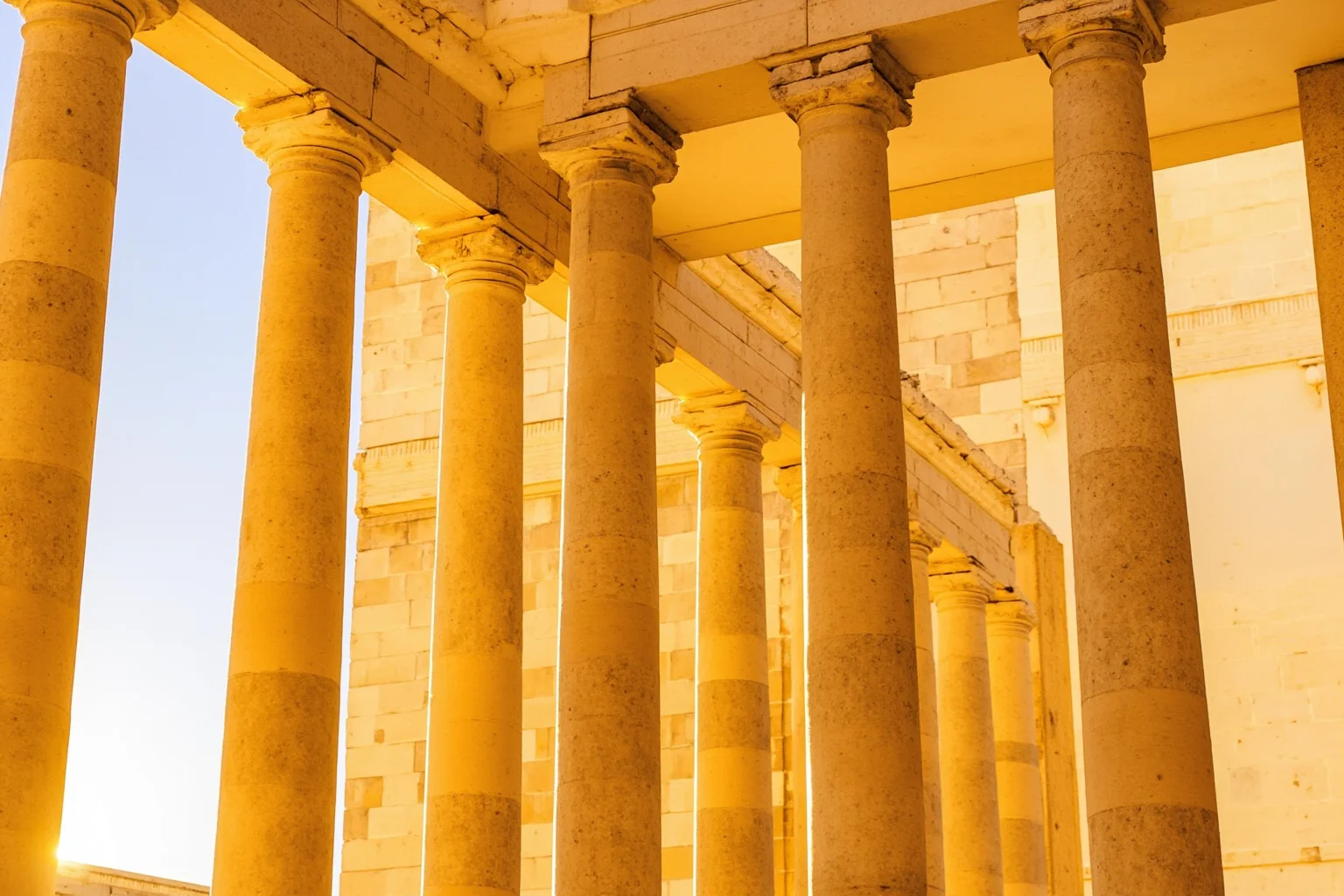 Close-up of golden-hued marble columns of a Greek temple glowing under bright Mediterranean sunlight