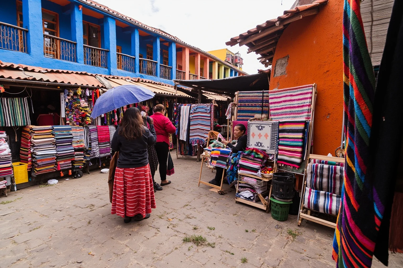 Colorful outdoor Andean market in Otavalo, Ecuador with woven textiles displayed on tables and indigenous vendors