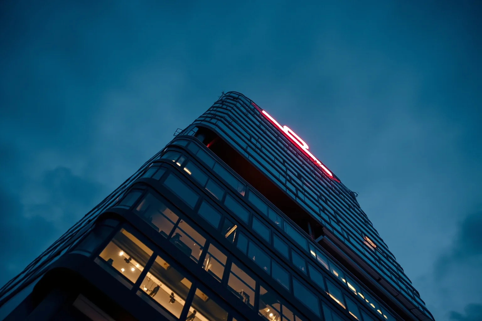 Corporate skyscraper with a company logo lit up at dusk, symbolizing a collapsing energy corporation