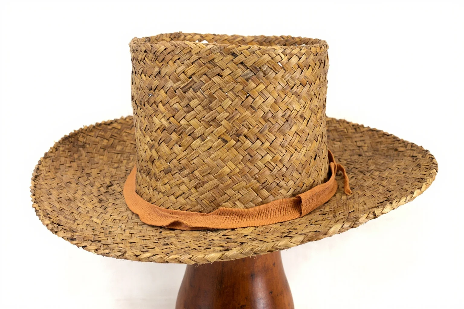 Early 1800s straw hat with silk weaving detail, displayed on a wooden stand