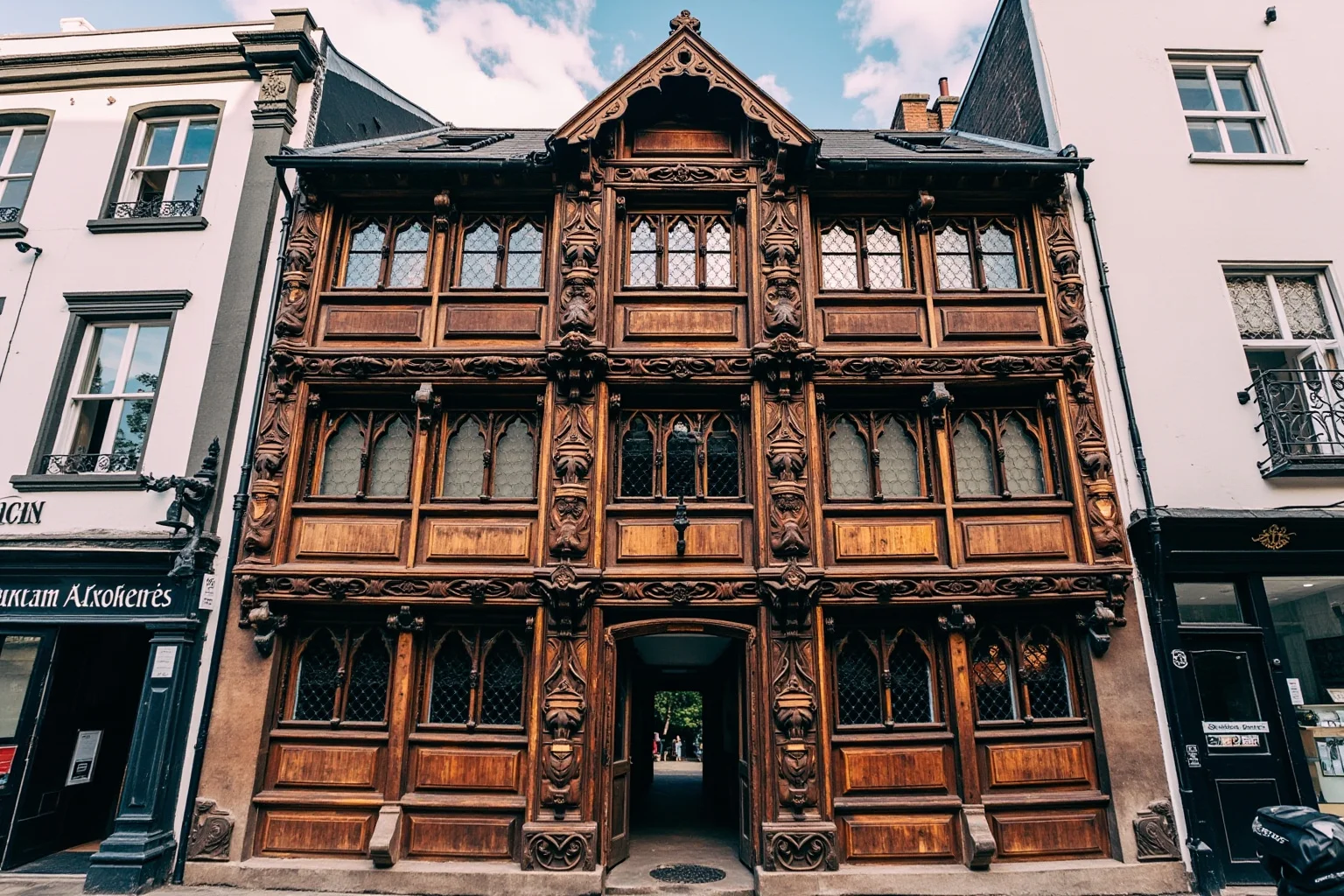 Elaborately carved timber-framed Jacobean English inn facade with ornate woodwork, striking historic street view