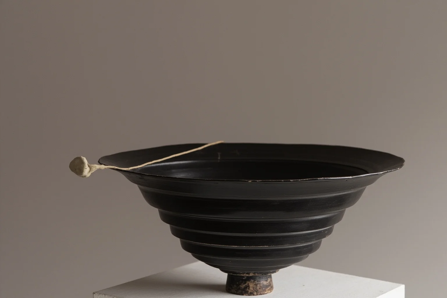 Extremely thin black wheel-turned pottery vessel displayed on a pedestal
