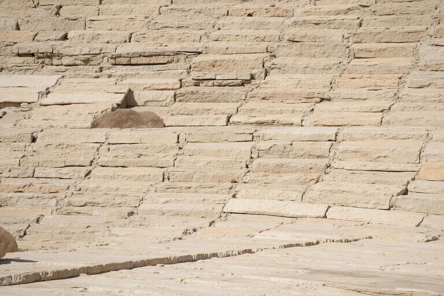 Fine-grained pale limestone quarry with thin flat rock slabs stacked in layers