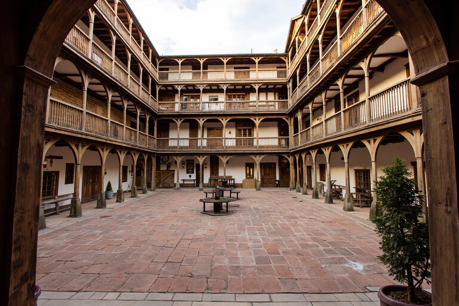 Galleried medieval English inn courtyard with wooden balconies wrapping around a central yard, coaching inn atmosphere