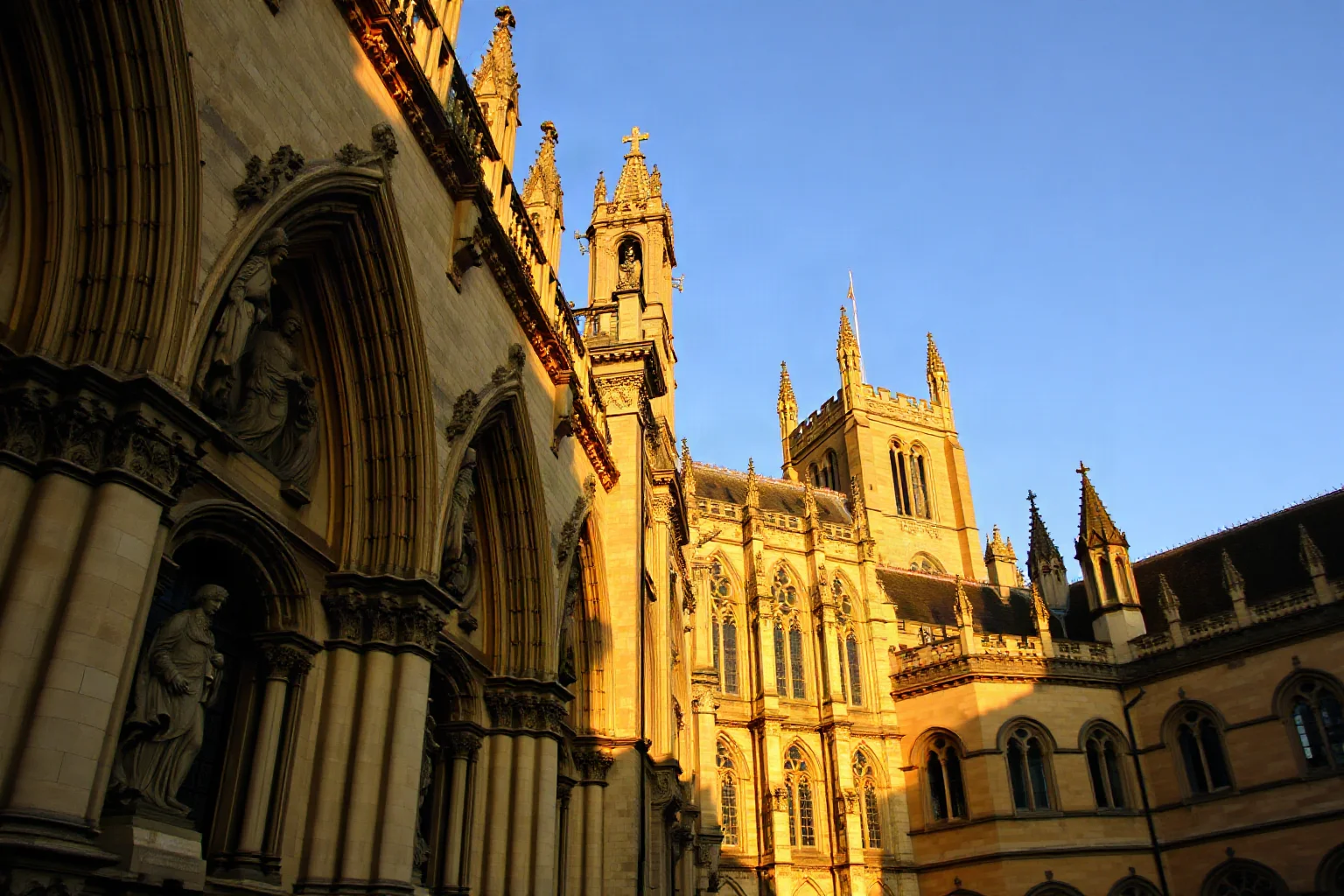 Gothic cathedral facade covered in rows of medieval stone statues, West Country England, golden hour lighting