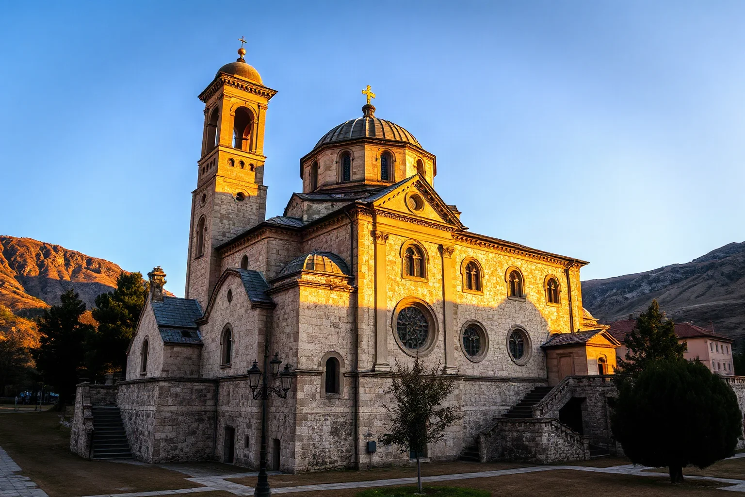 Grand ancient stone cathedral with domed roof in the Caucasus mountains, monastic architecture, golden afternoon light