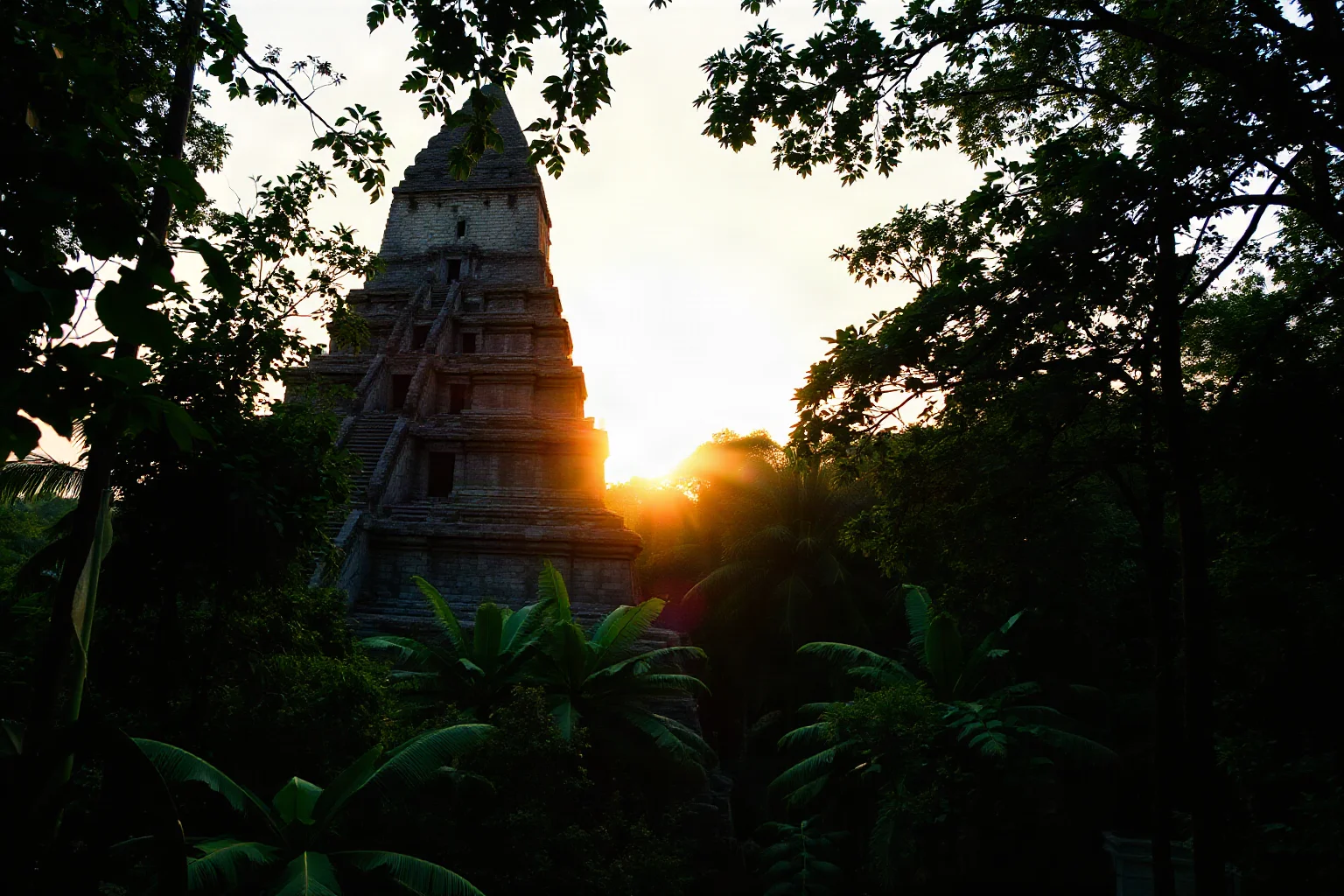 Grand stepped stone pyramid rising above dense green jungle canopy at sunrise