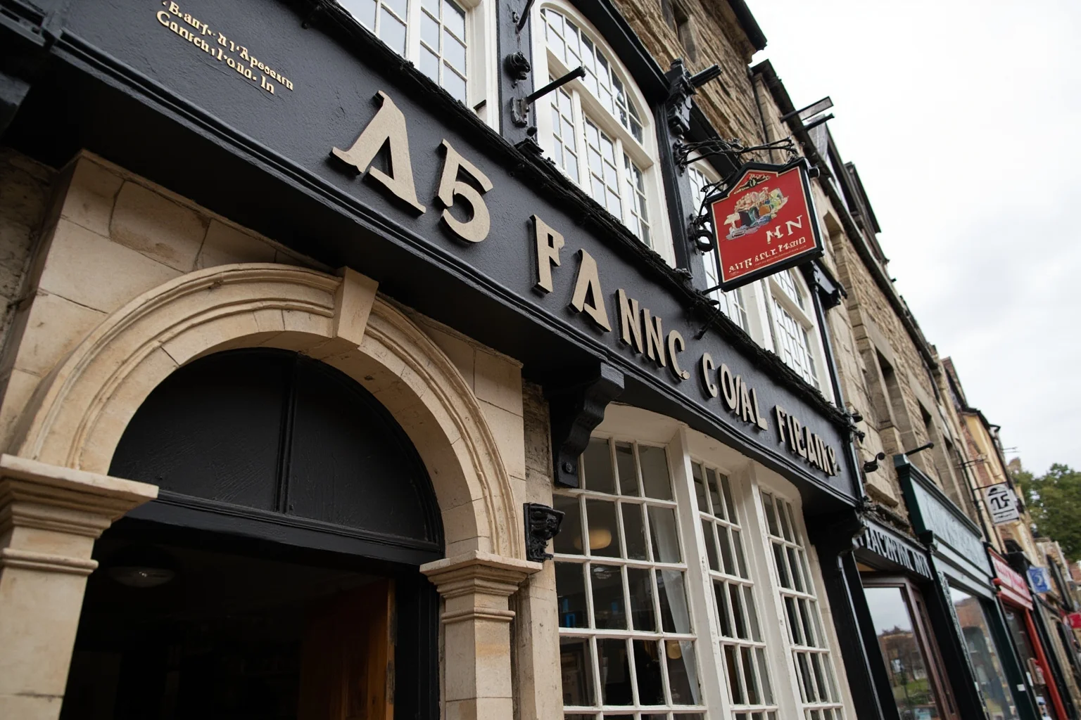 Historic English coaching inn facade with stone archway and hanging inn sign, medieval market town street scene