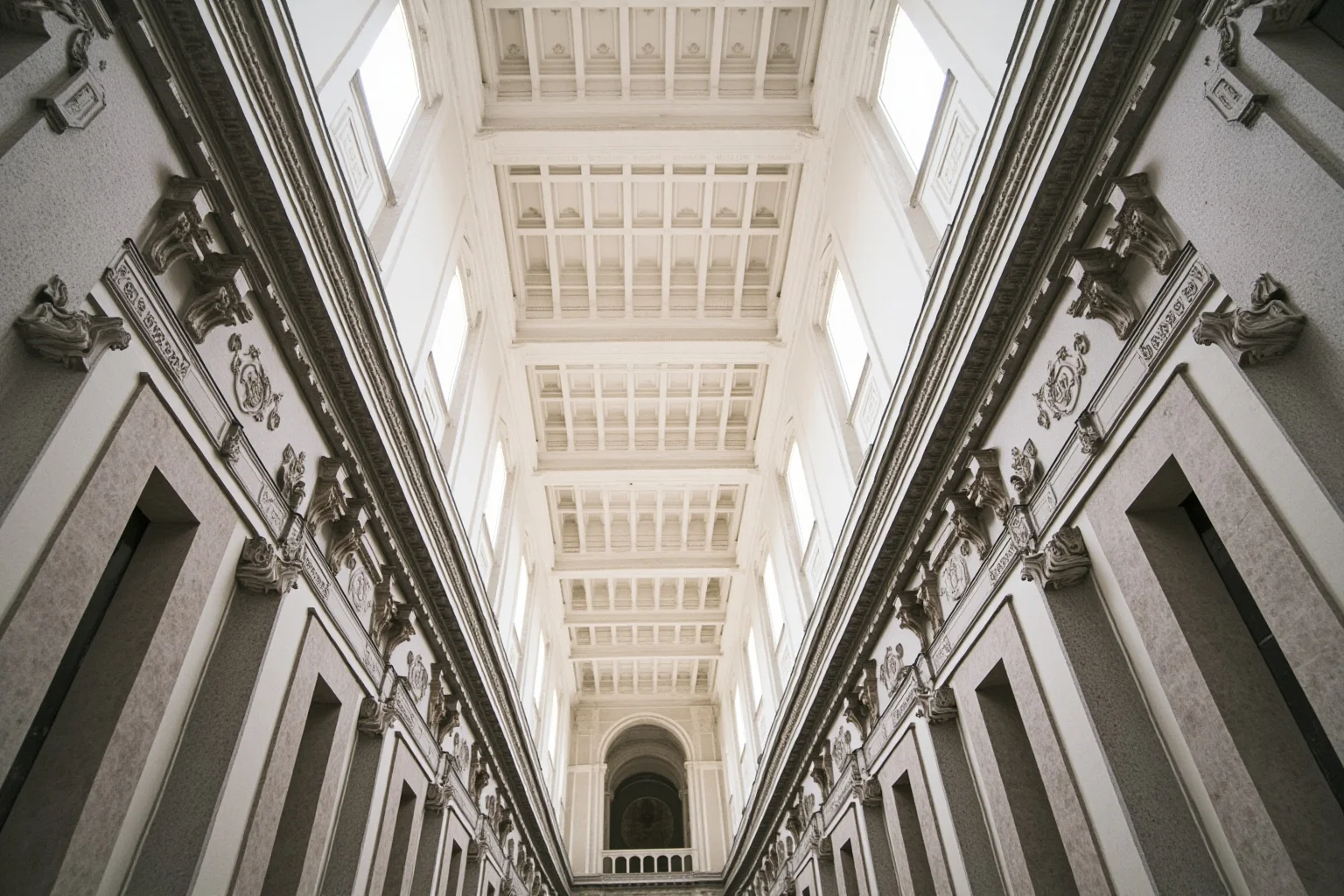Interior of a Renaissance basilica with gray stone pilasters, coffered ceiling, and white plaster walls in geometric harmony