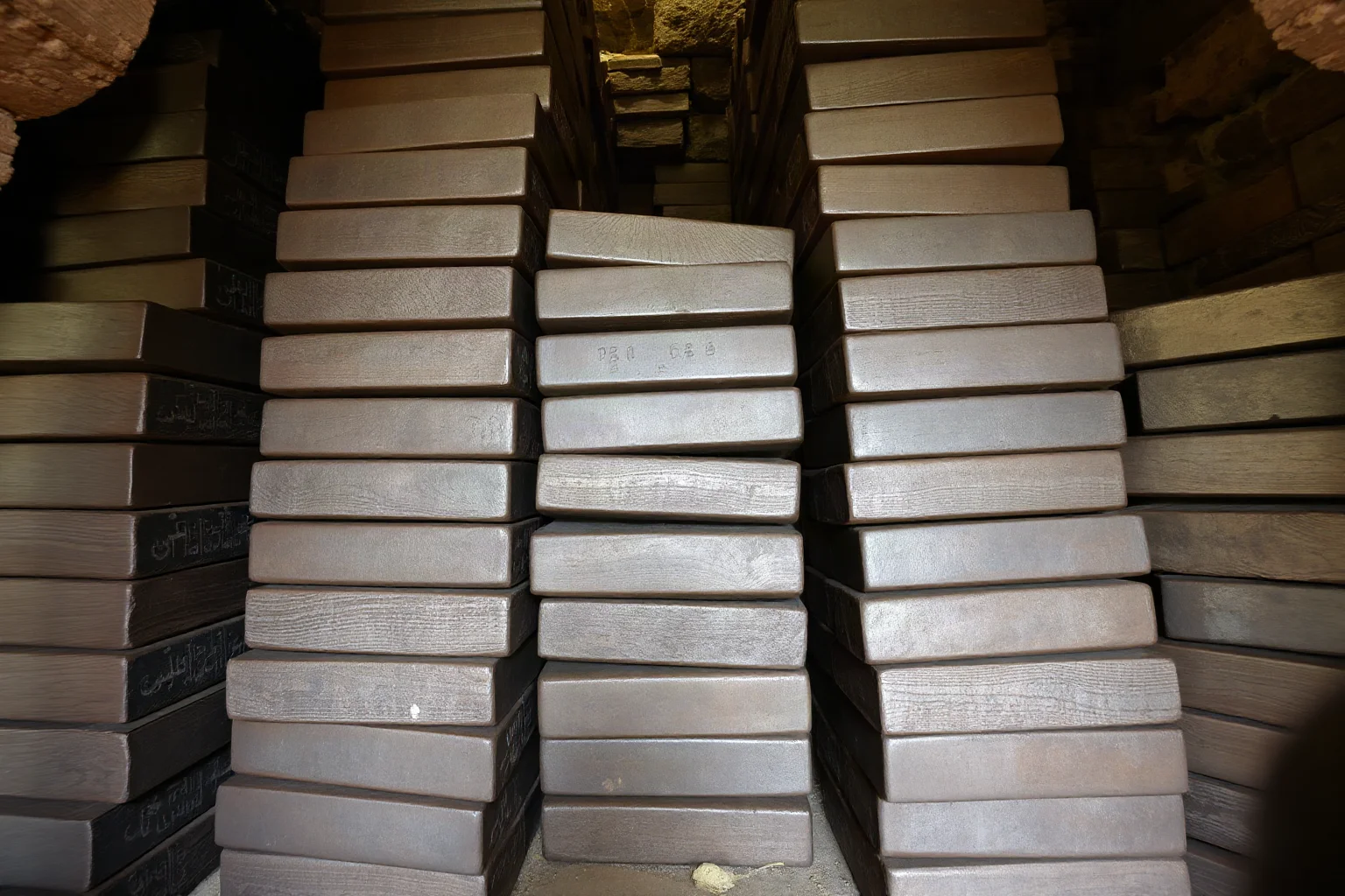 Large heavy iron bars stacked as ancient currency in a stone treasury room