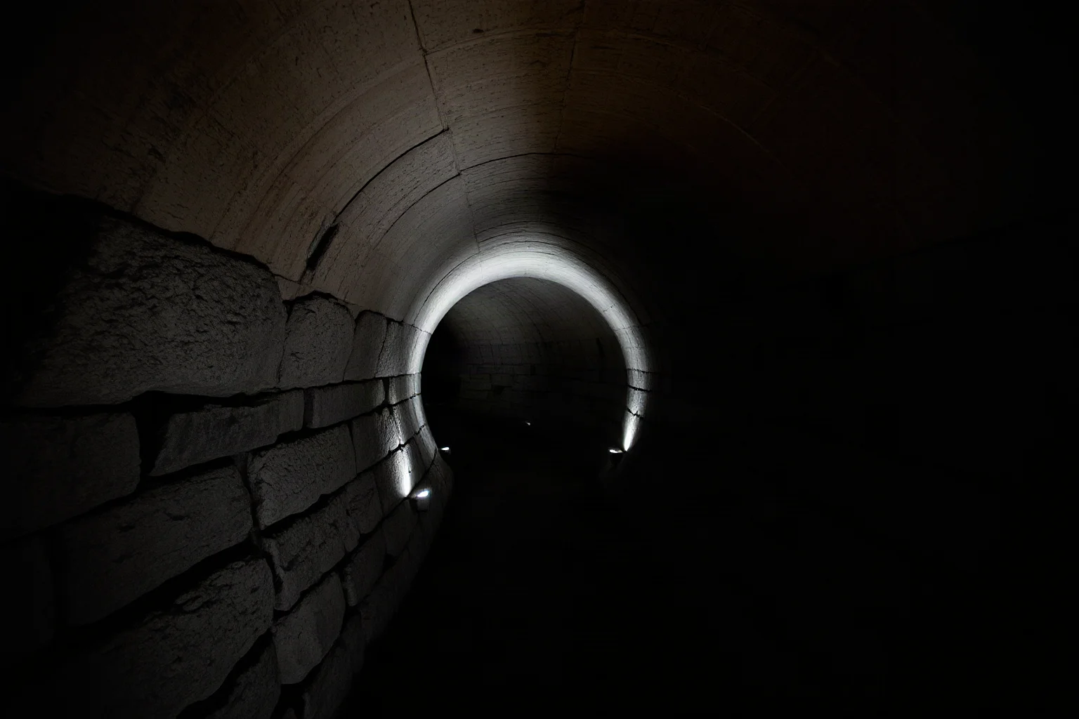 Long curving stone corridor leading into a hidden underground tomb