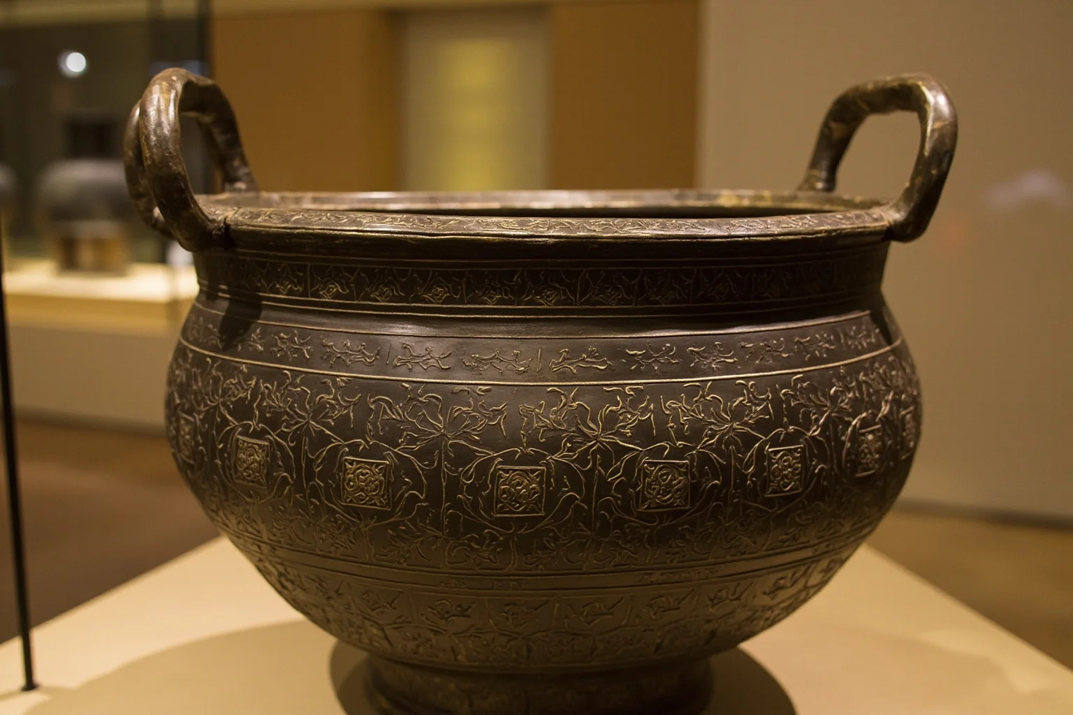 Massive bronze ritual cooking vessel with intricate engraved patterns, museum display