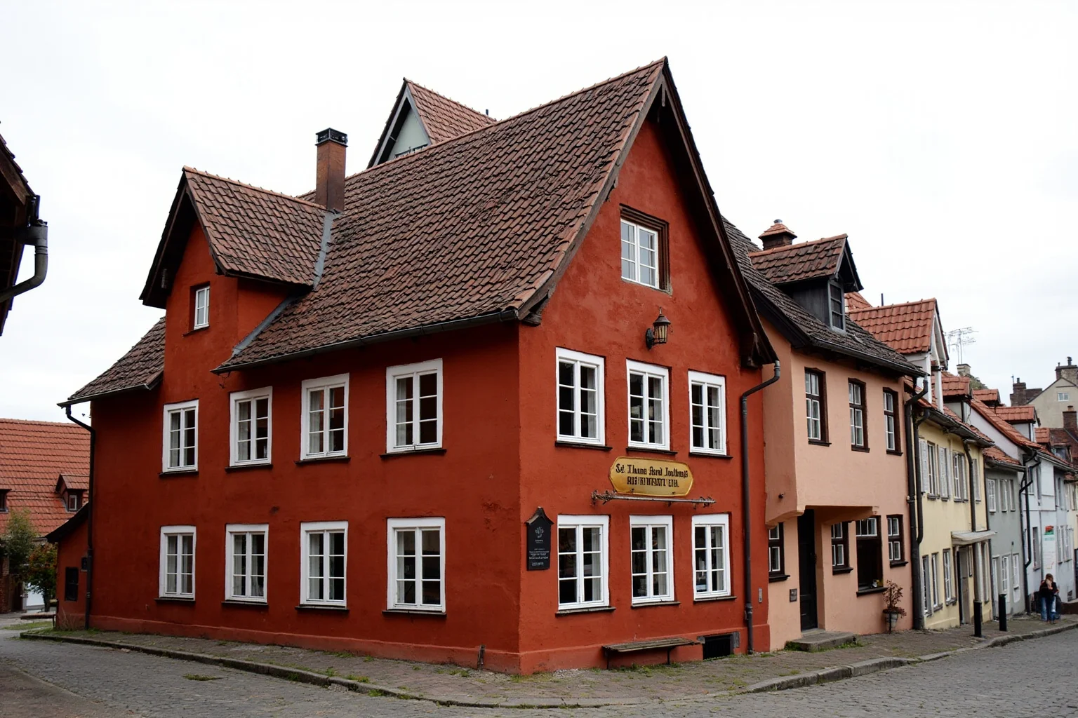 Medieval German inn with red-painted facade and steep gabled roof on a cobblestone street in an old European town