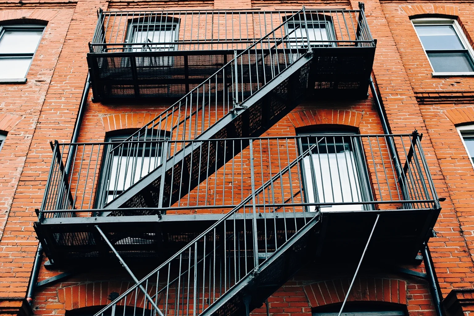 Metal fire escape structure on historic brick building facade, external stairway and platforms