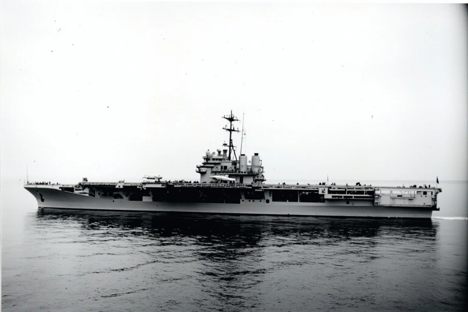 The Longest-Serving Warships of All Time 17 Mid-20th-century aircraft carrier with flat flight deck and control tower, gray hull, at sea under overcast sky