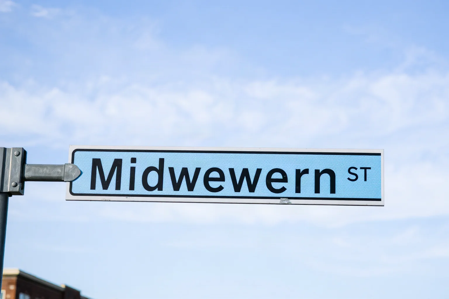 Modern city street sign reading a Midwestern American city name, with an old sailing ship silhouette in the background