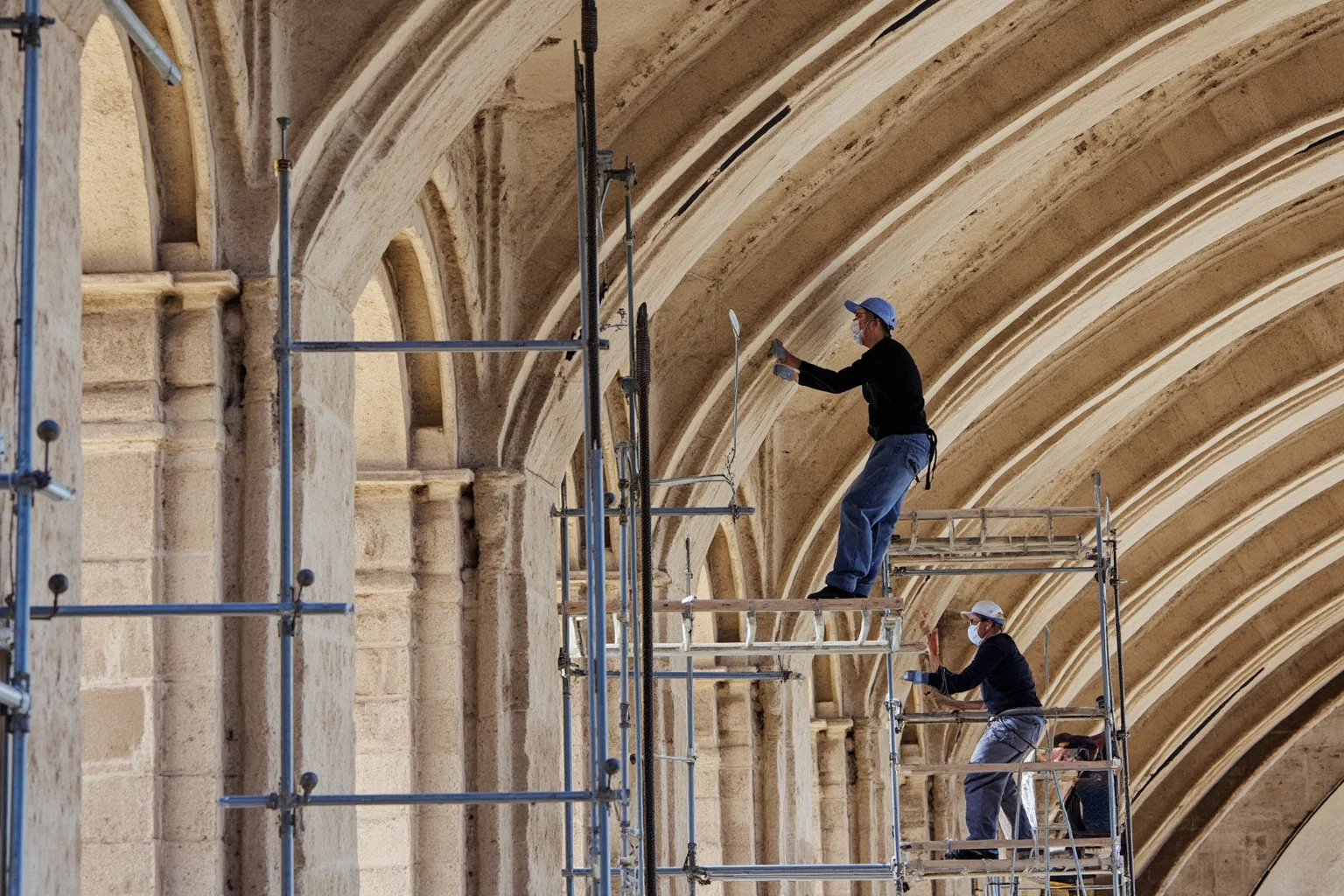 Modern conservators carefully restoring ancient stone arches with scaffolding and tools