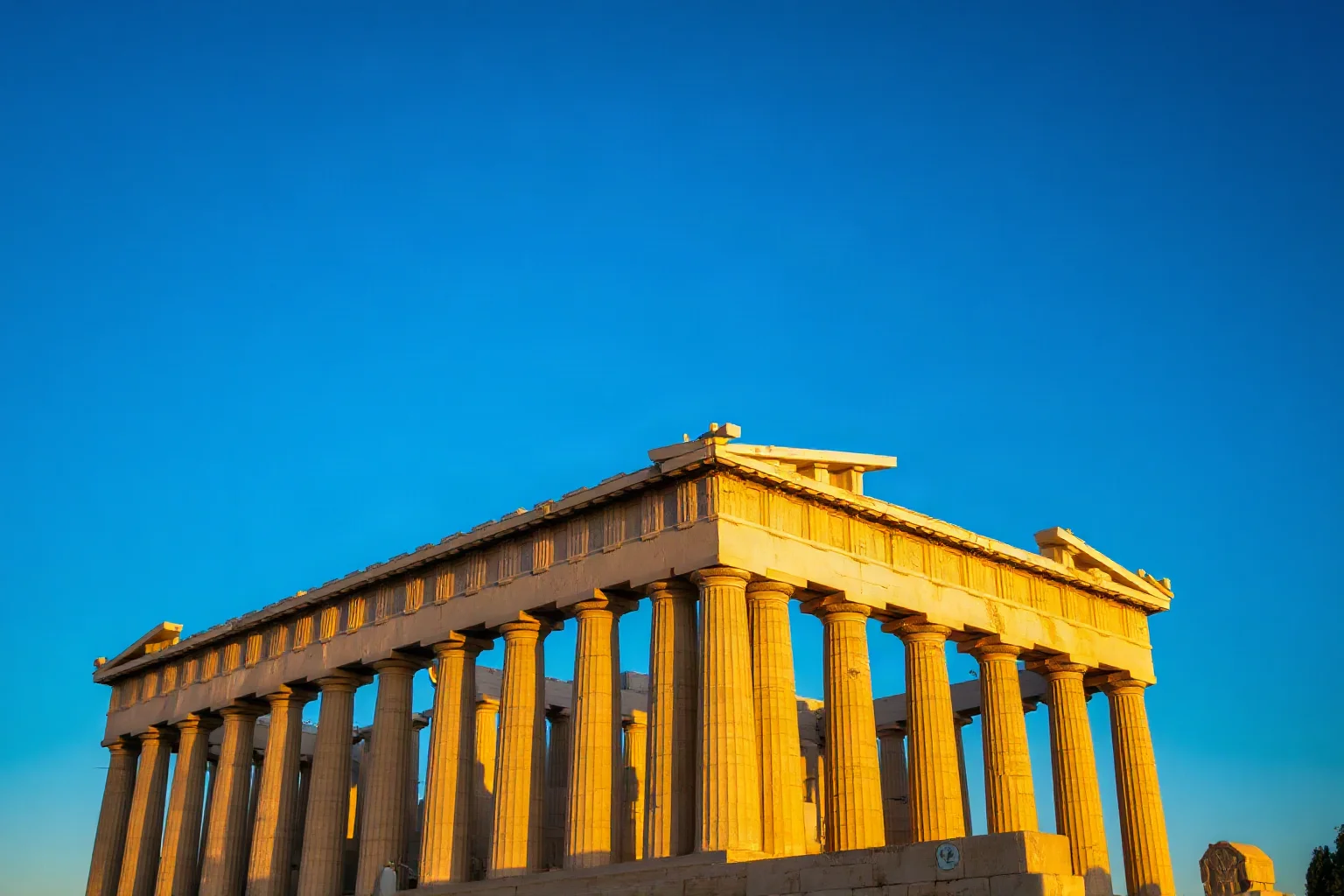The Parthenon temple on the Acropolis of Athens glowing in warm sunset light, classical Doric columns, blue sky
