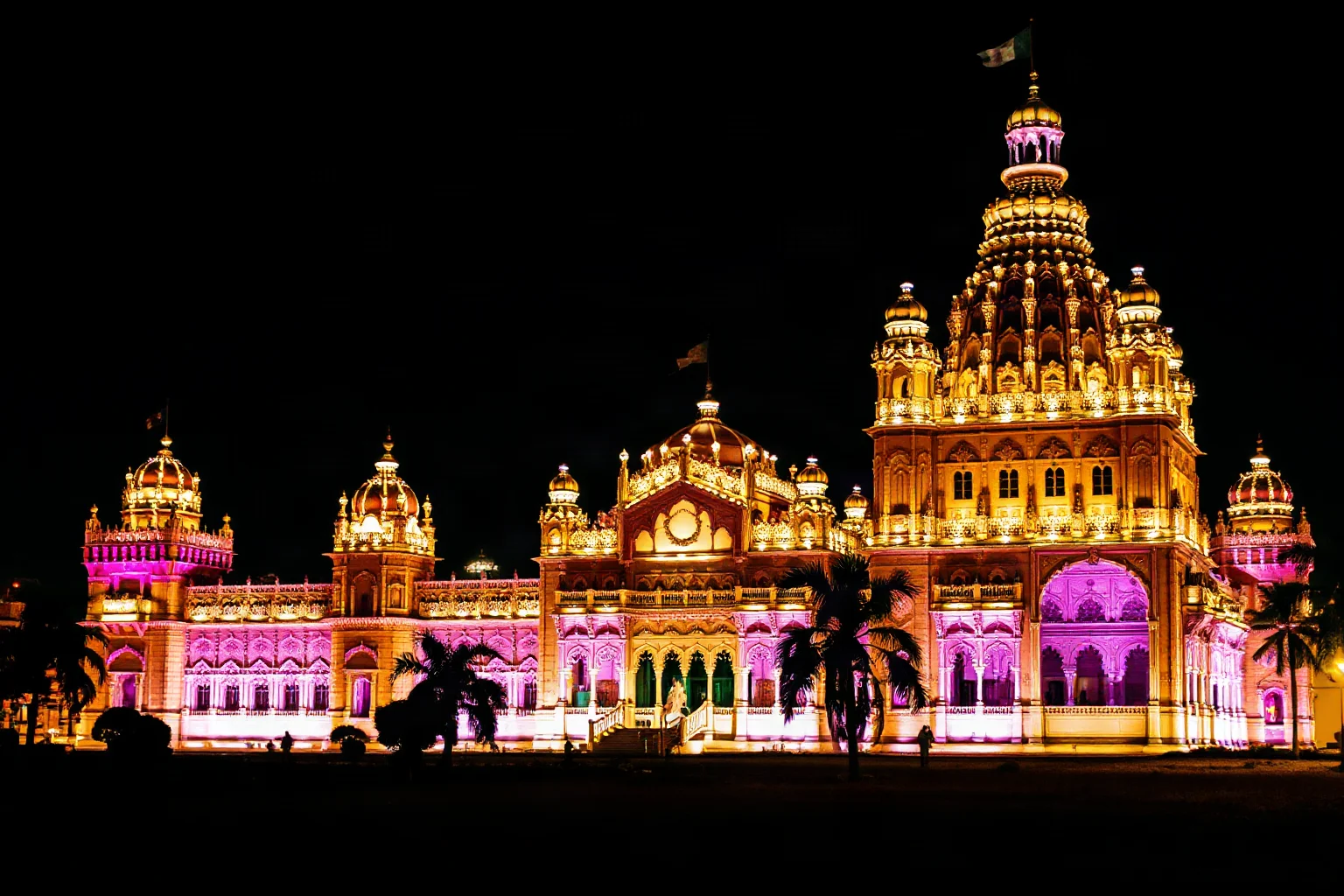 Mysore Palace at night illuminated with thousands of lights, showing its Indo-Gothic architecture in pink stone