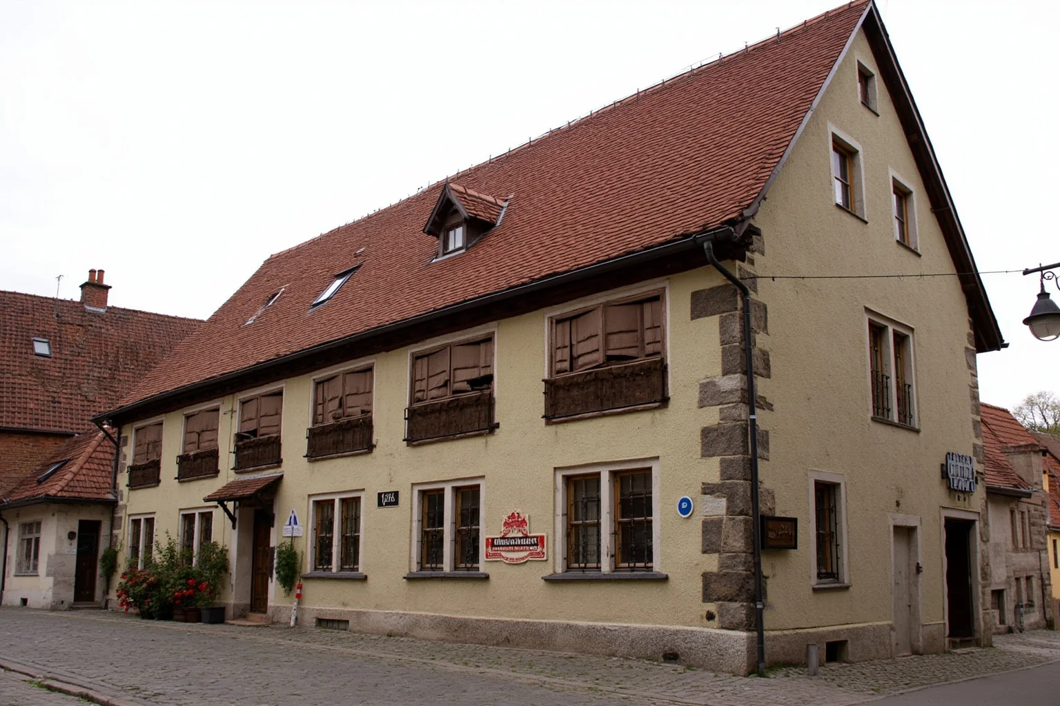 Old German pilgrim hospice building with steep red roof and small shuttered windows on a cobbled medieval street