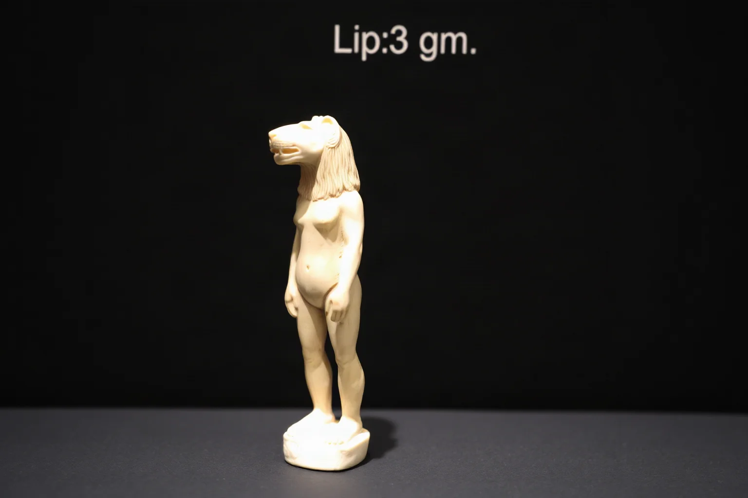 Small ivory carving of a figure with a lion's head and human body, displayed against a dark museum backdrop, prehistoric art style