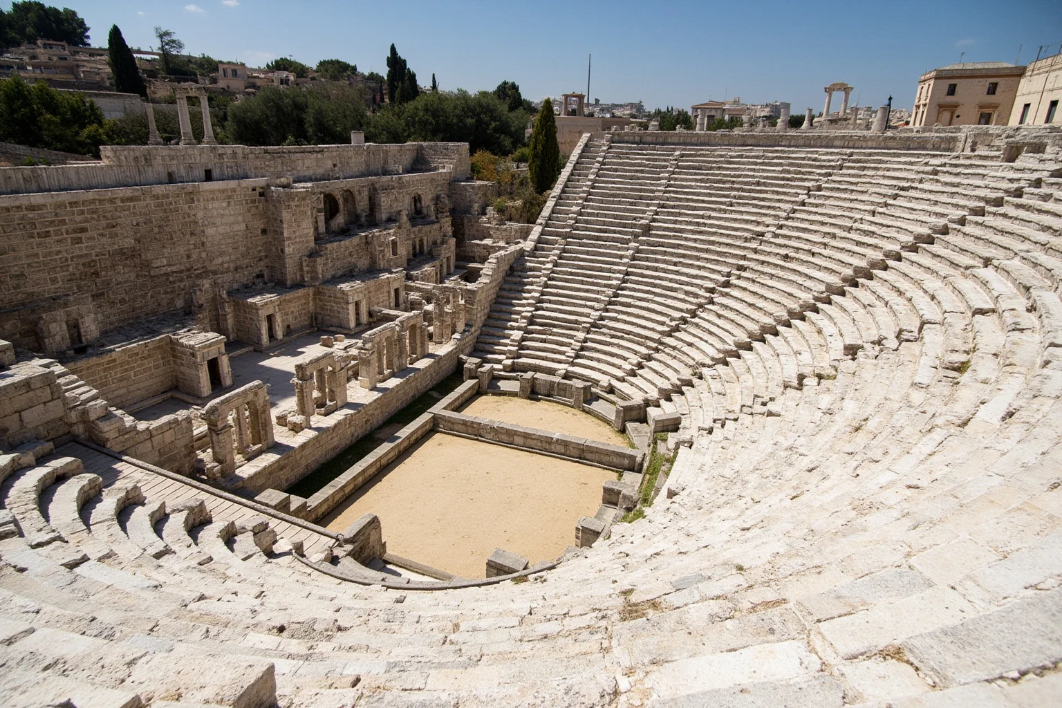 Wide daylight photo of the ancient Theatre of Dionysus ruins on the slope of the Acropolis in Athens, stone seating rows and columns visible