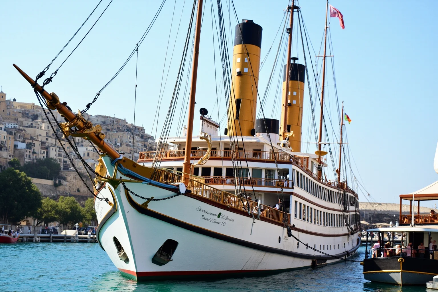 The Longest-Serving Warships of All Time 4 Ornate 19th-century royal steam yacht with elegant white hull, gold trim, and tall smokestack, docked in a Mediterranean-style harbor