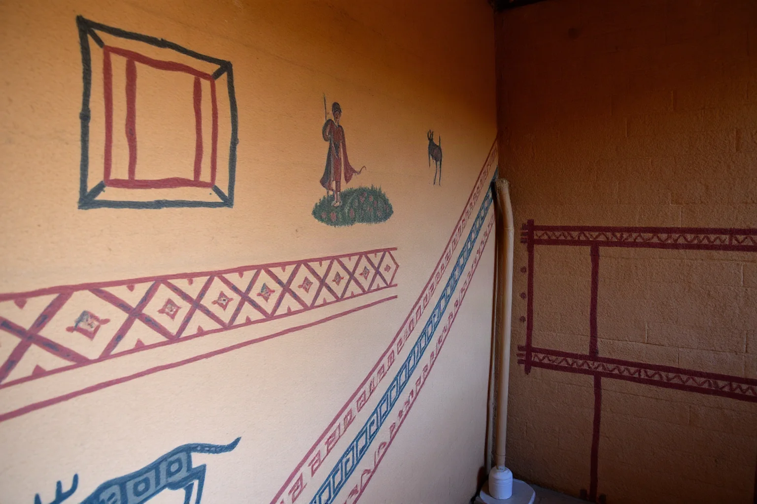 Plastered mudbrick walls with painted geometric patterns, hunting scenes, and early landscape or town-plan imagery from an ancient settlement
