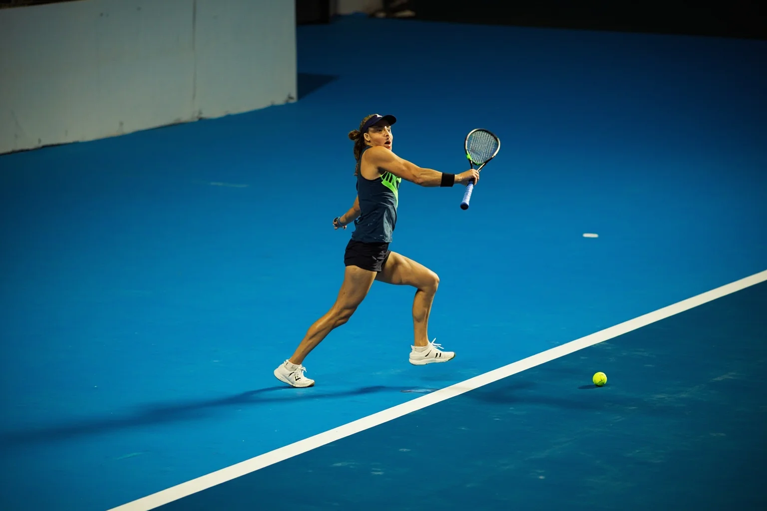Female Athletes In History Who Changed The Game 22 Powerful female tennis player mid-forehand swing on a blue hardcourt, intense focus, modern stadium lighting