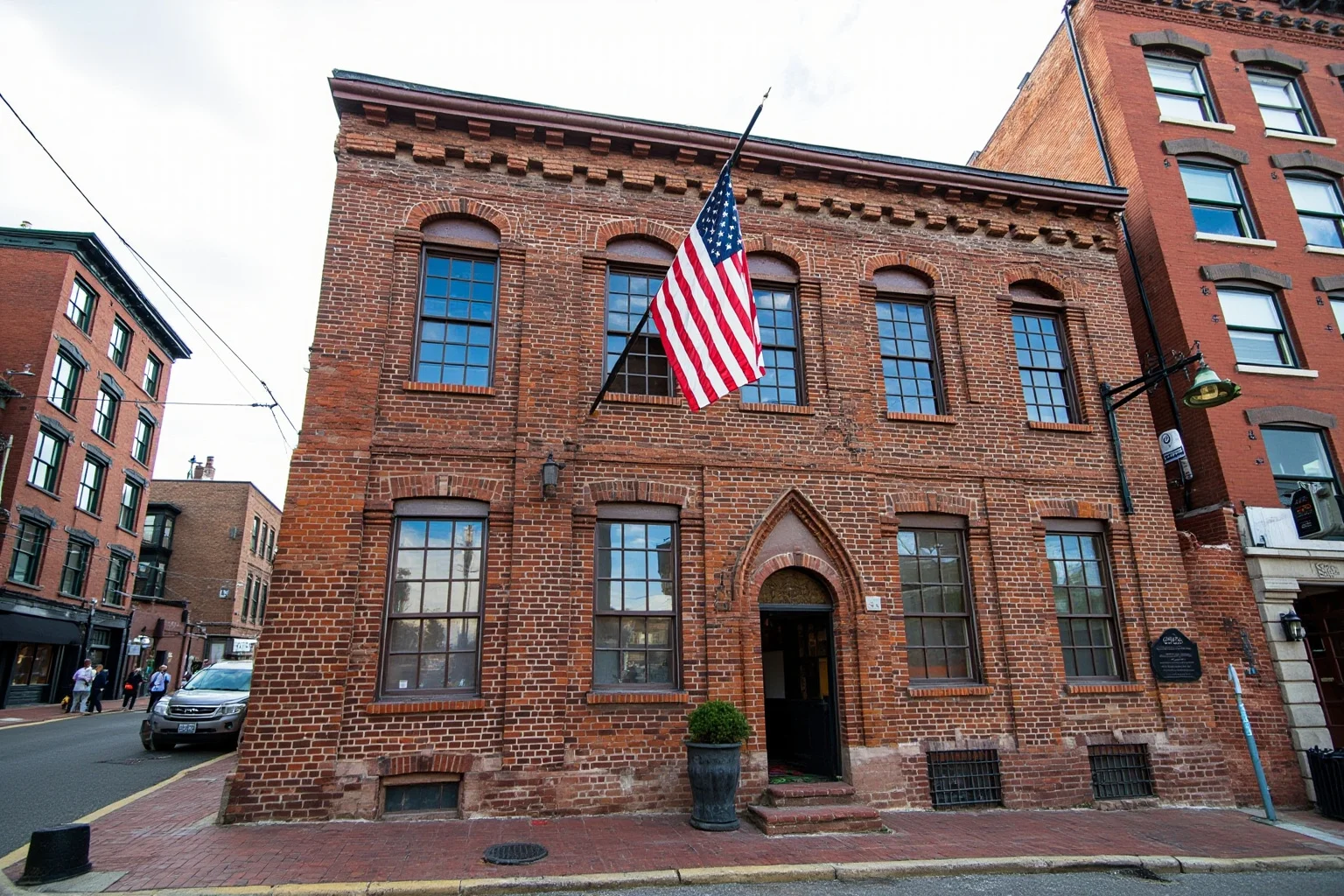 Reconstructed 18th-century brick tavern with tall windows and a Colonial American flag, historic Philadelphia streetscape