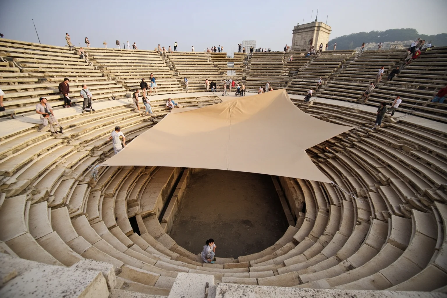 Roman sailors operating ropes to extend a canvas awning over amphitheater seating