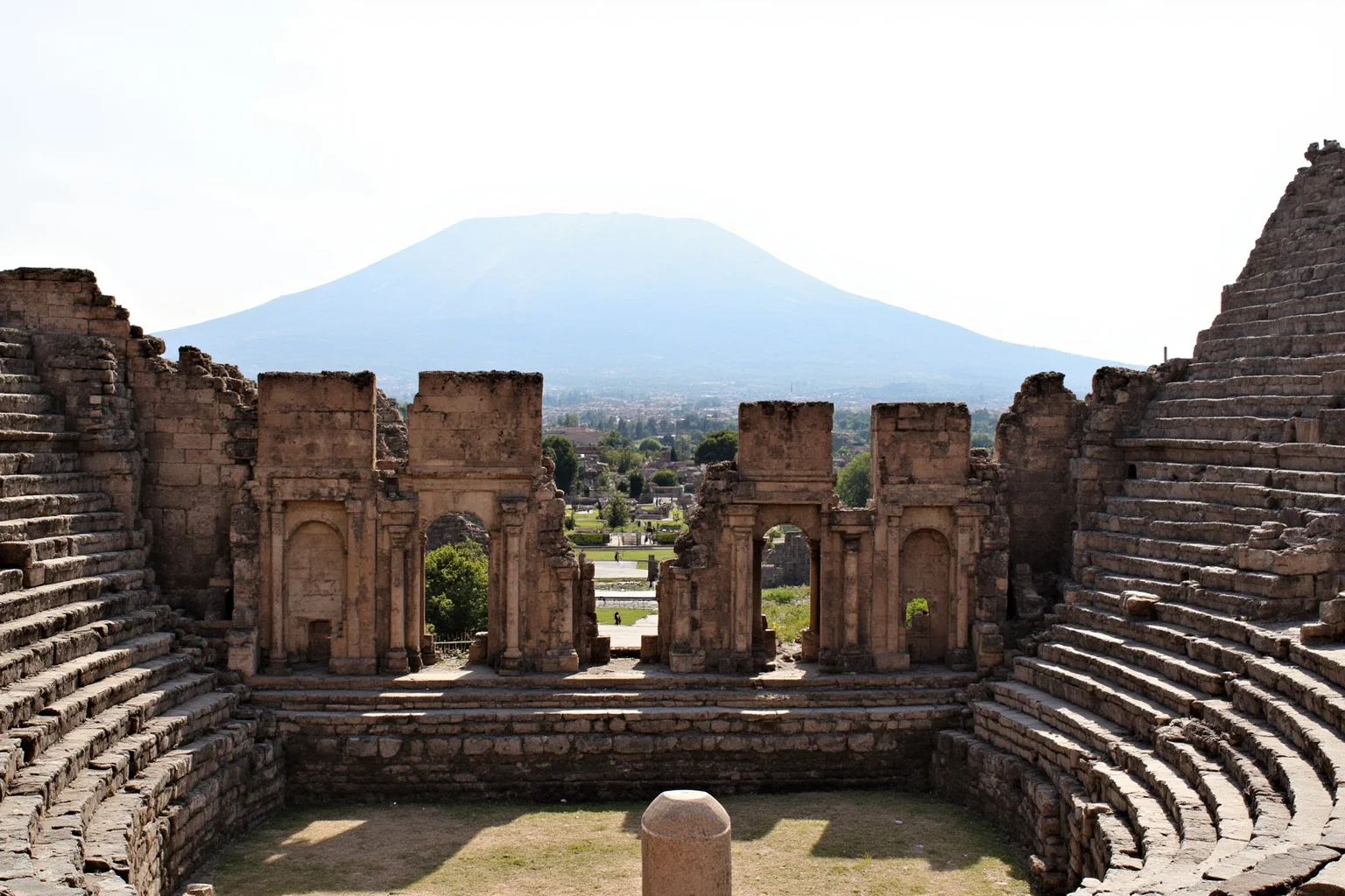 Roman Teatro Grande theatre ruins in Pompeii with volcanic Mount Vesuvius visible in the distance