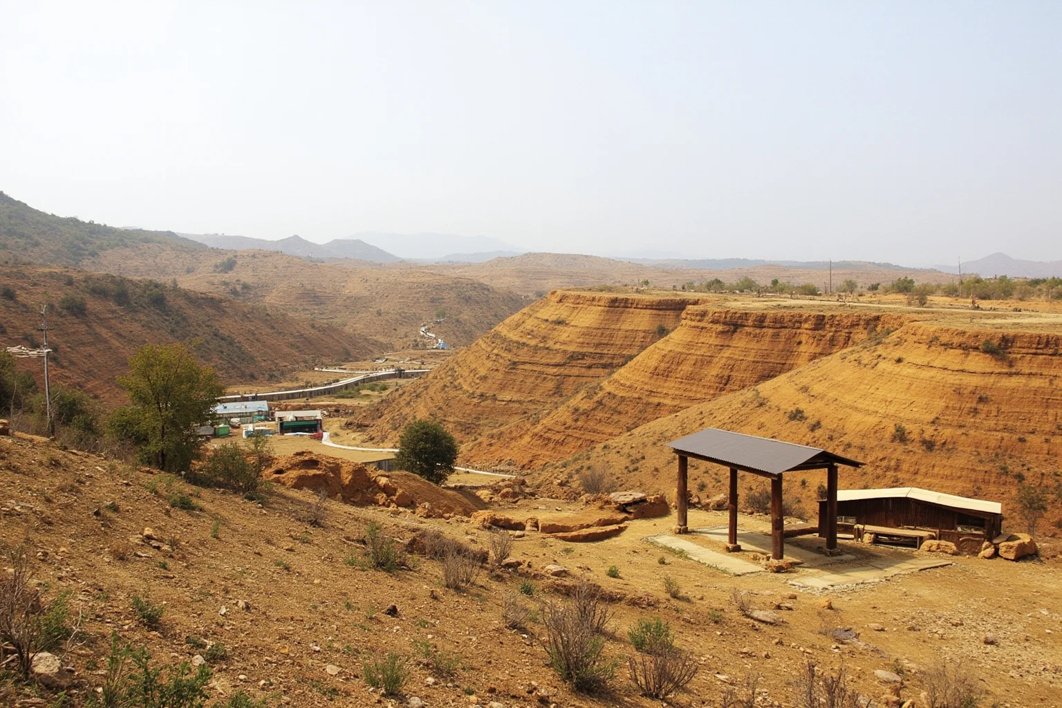 Rural Chinese basin landscape with sedimentary hills and an open-air fossil museum structure